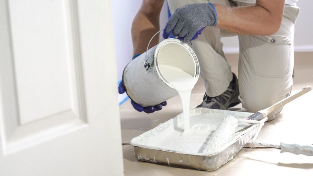 pouring white paint into tray