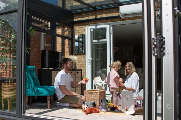 conservatory being used as a children's playroom with family playing with toys